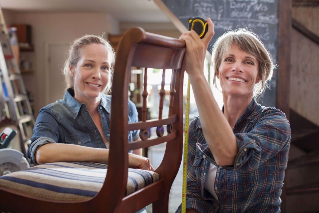 dwie kobiety mierzące drewniane krzesło