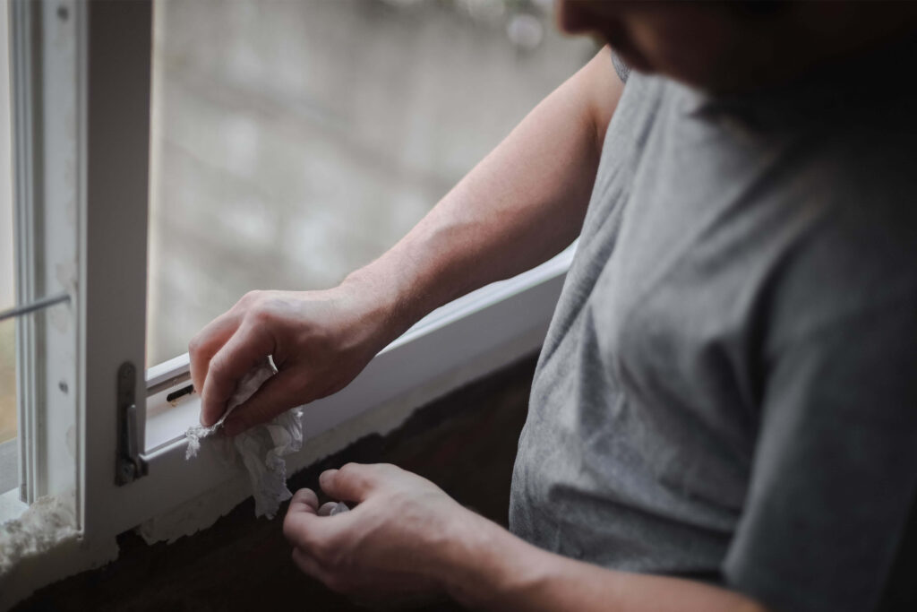 mężczyzna czyszczący ramę okienną