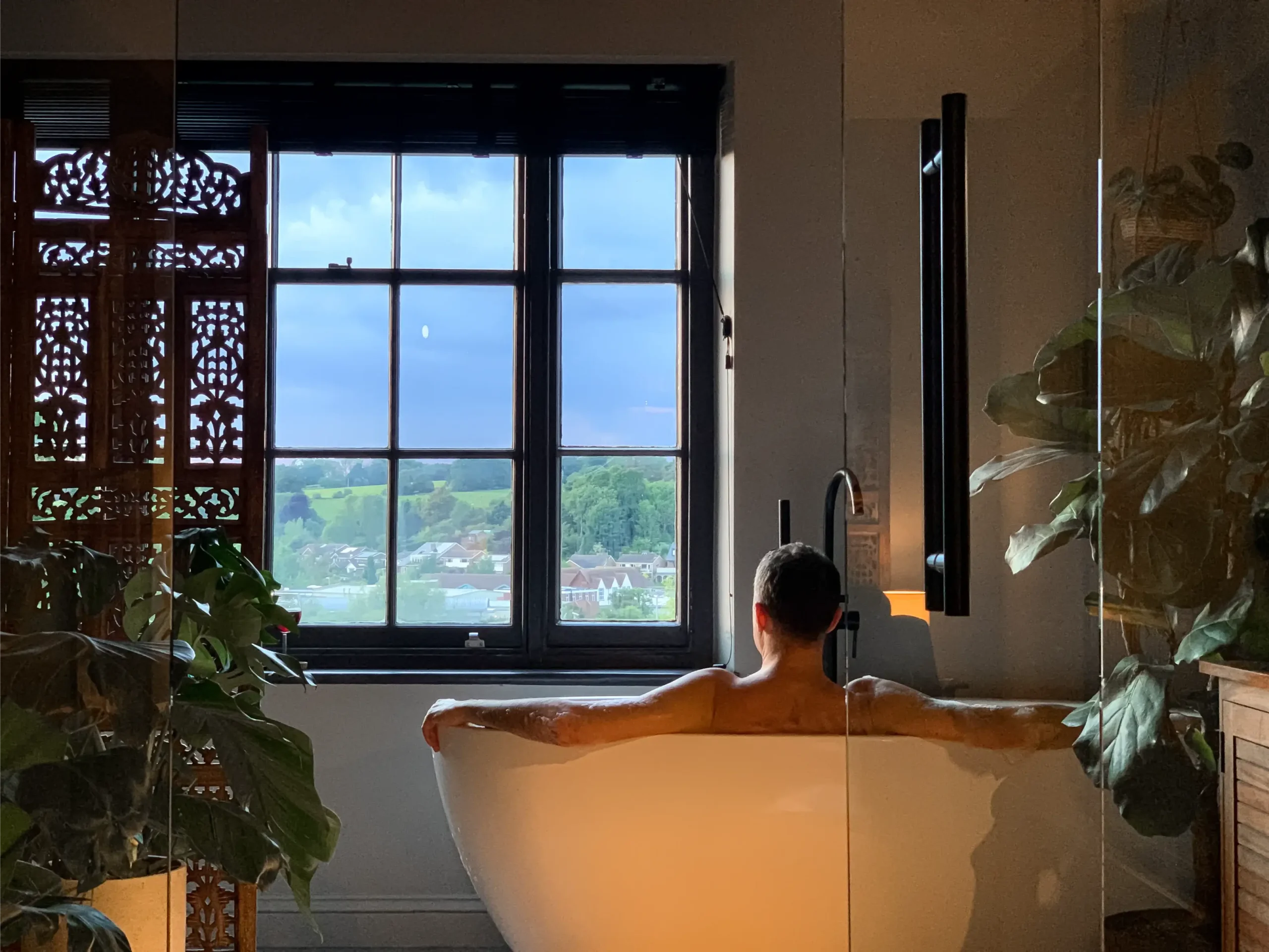 mężczyzna siedzący w wannie przy oknie z folią lustrzaną